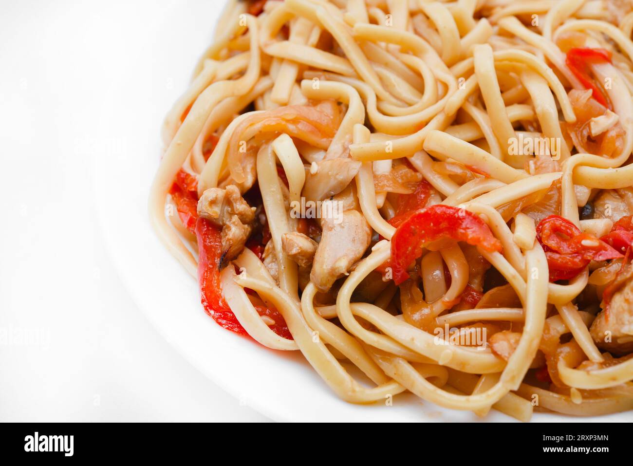 Tagliatelle coreane Udon con carne su un piatto bianco. Deliziosa colazione a base di carne piccante. Foto Stock