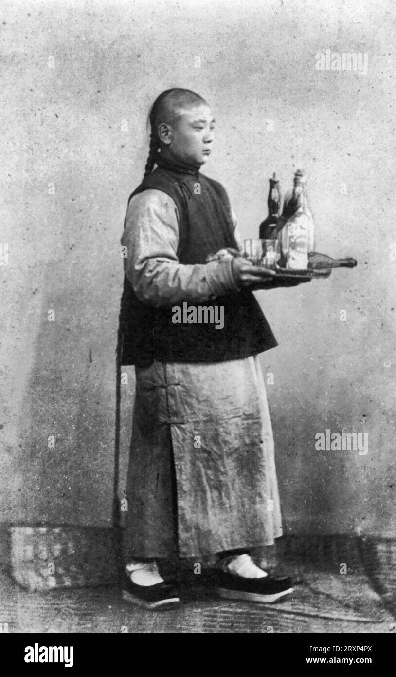 Ragazzo con vassoio - la fotografia mostra un uomo cinese, ritratto a tutta lunghezza, in piedi, rivolto verso destra, con un vassoio su cui sono presenti bottiglie per cocktail, intorno al 1870 Foto Stock