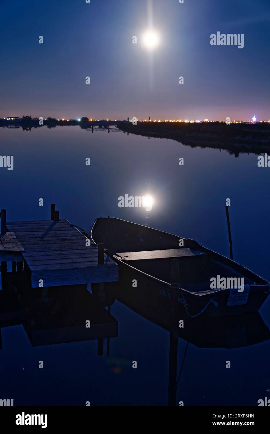 Luna che splende sulla barca ormeggiata nello stagno di Etang de lArnel di notte, Herault, Francia Foto Stock