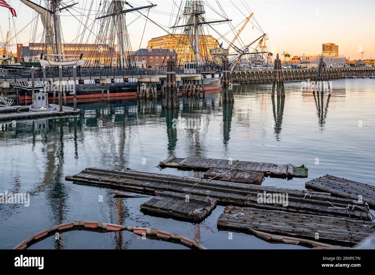 Paesaggio urbano della barriera galleggiante sui pontoni della baia con un molo di legno e infrastrutture portuali con edifici di magazzini e gru nel vecchio indo Foto Stock