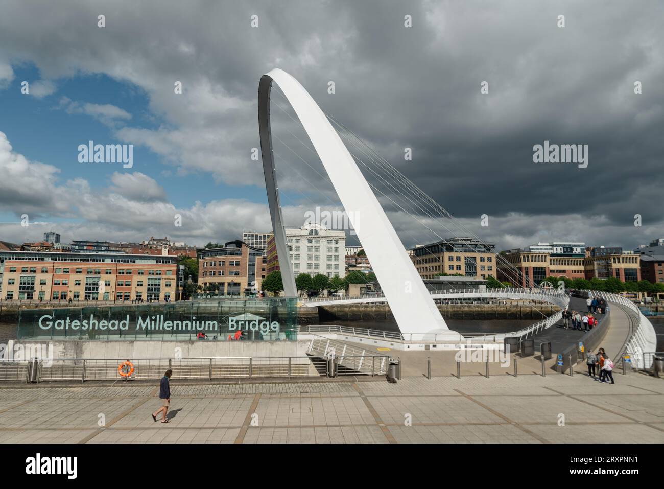 Newcastle upon Tyne, Regno Unito - 30 agosto 2023: Una singola passeggiata individuale davanti all'insegna del Gateshead Millenium Bridge sulla strada per attraversare Foto Stock