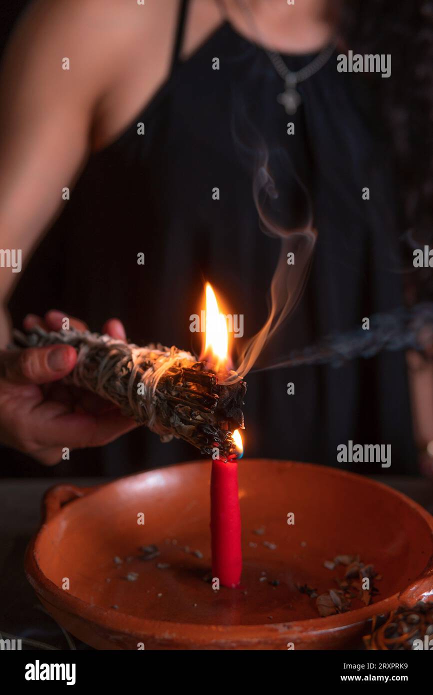 Accendendo un incenso, strega alla vigilia di tutti i santi che esegue un rituale di pulizia, Halloween, credenze spirituali, magia bianca Foto Stock
