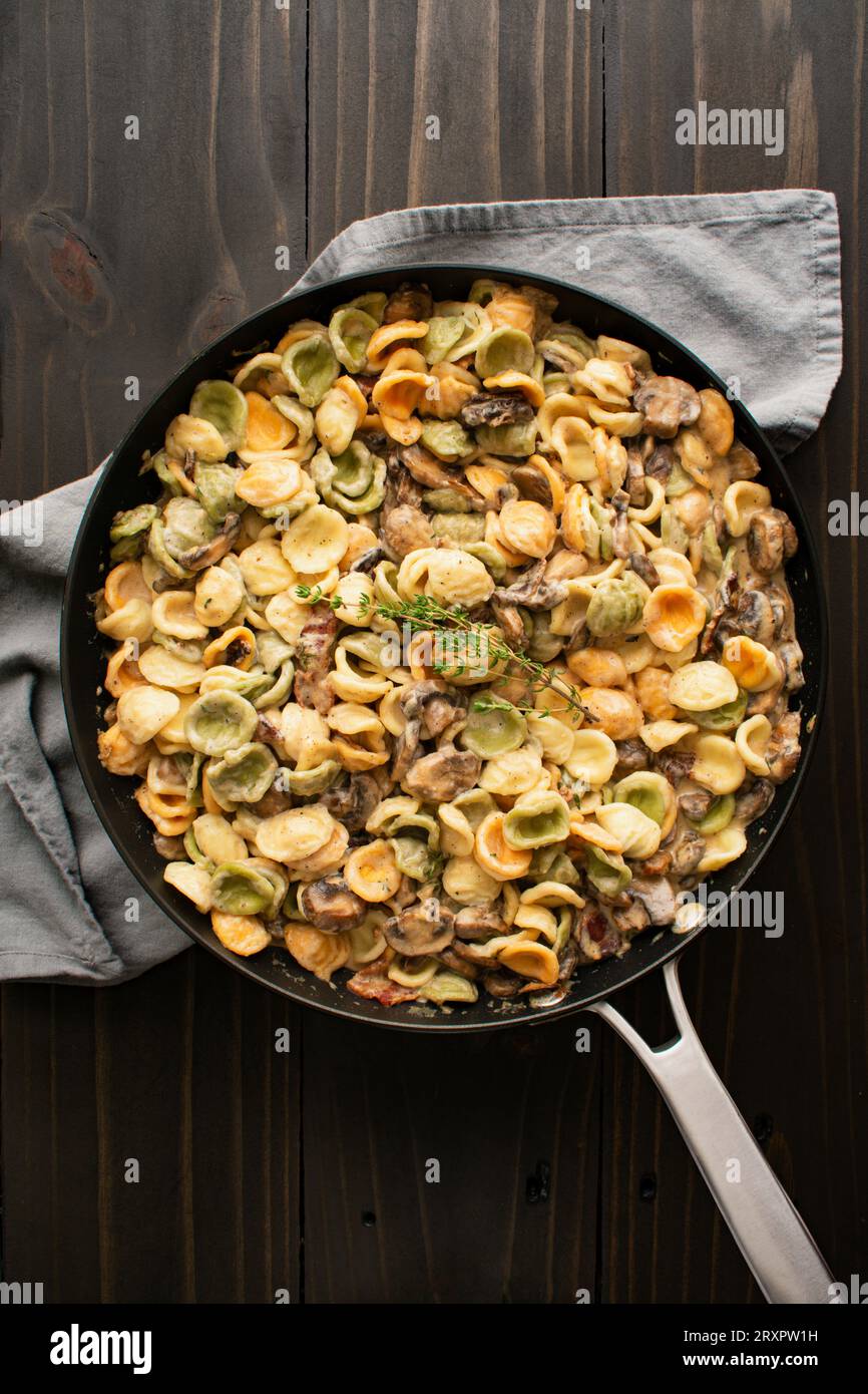 Orecchiette con salsa Thyme ai funghi in uno Skillet: Pasta e funghi in salsa panna serviti in una grande padella di saltatura Foto Stock