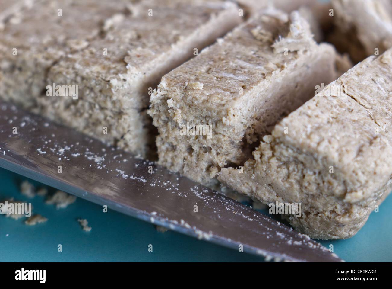 Ravvicinati con un coltello a fette di halva di girasole. Foto Stock
