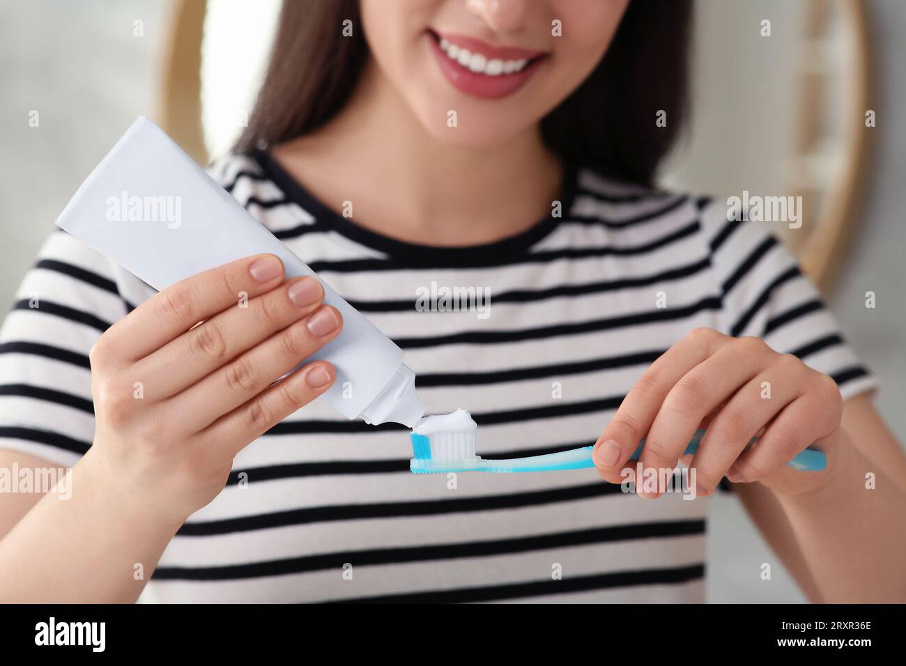 Donna che strizza dentifricio dal tubo allo spazzolino elettrico in bagno,  primo piano Foto stock - Alamy