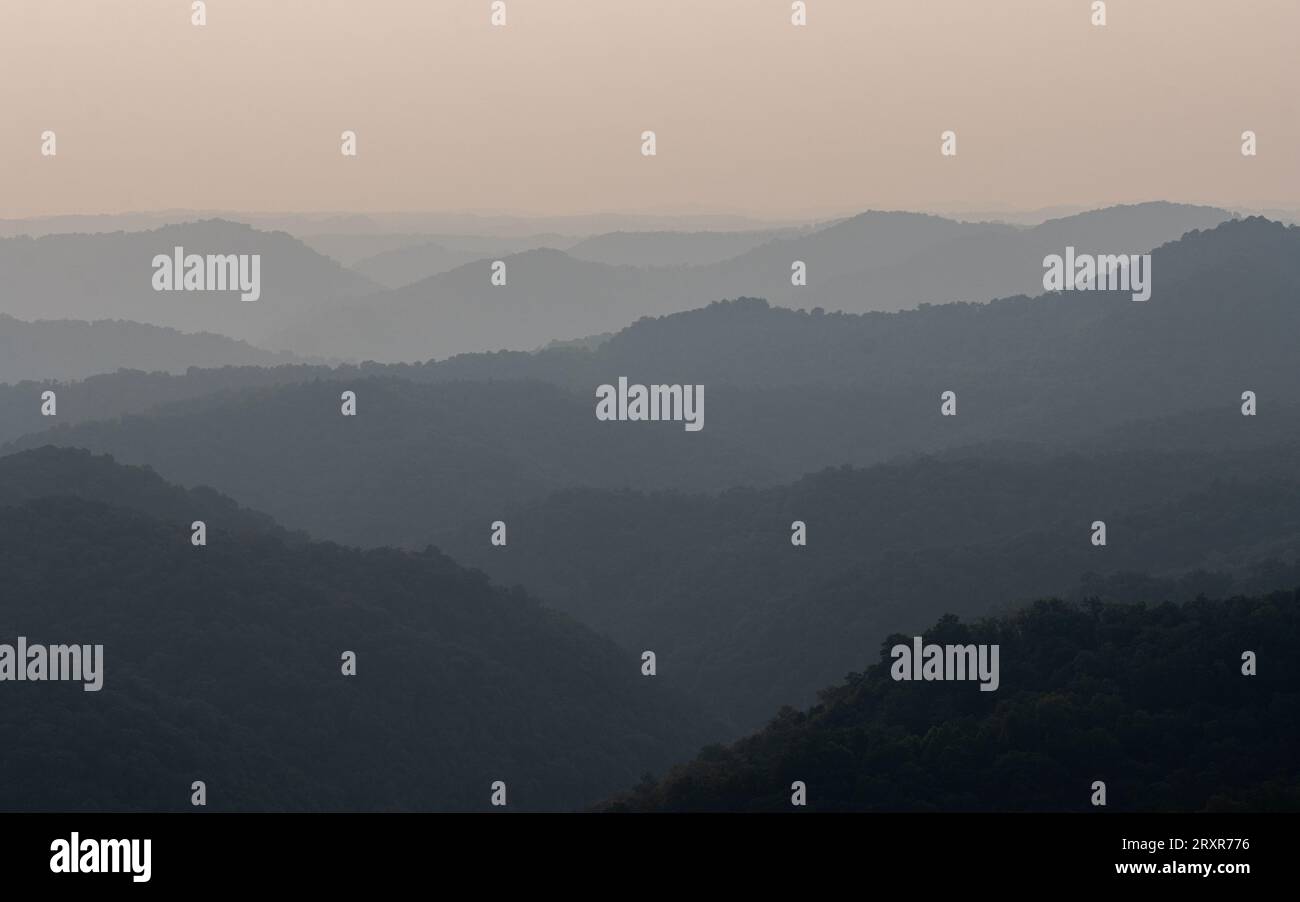 Il sole tramonta sopra le creste di montagna. Foto Stock