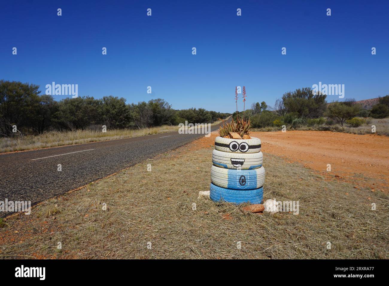 Un vaso di piante fatto di pneumatici di gomma per auto dipinte come un minion tratto dal film Dregicable me lungo la strada rurale nell'entroterra australiano Foto Stock