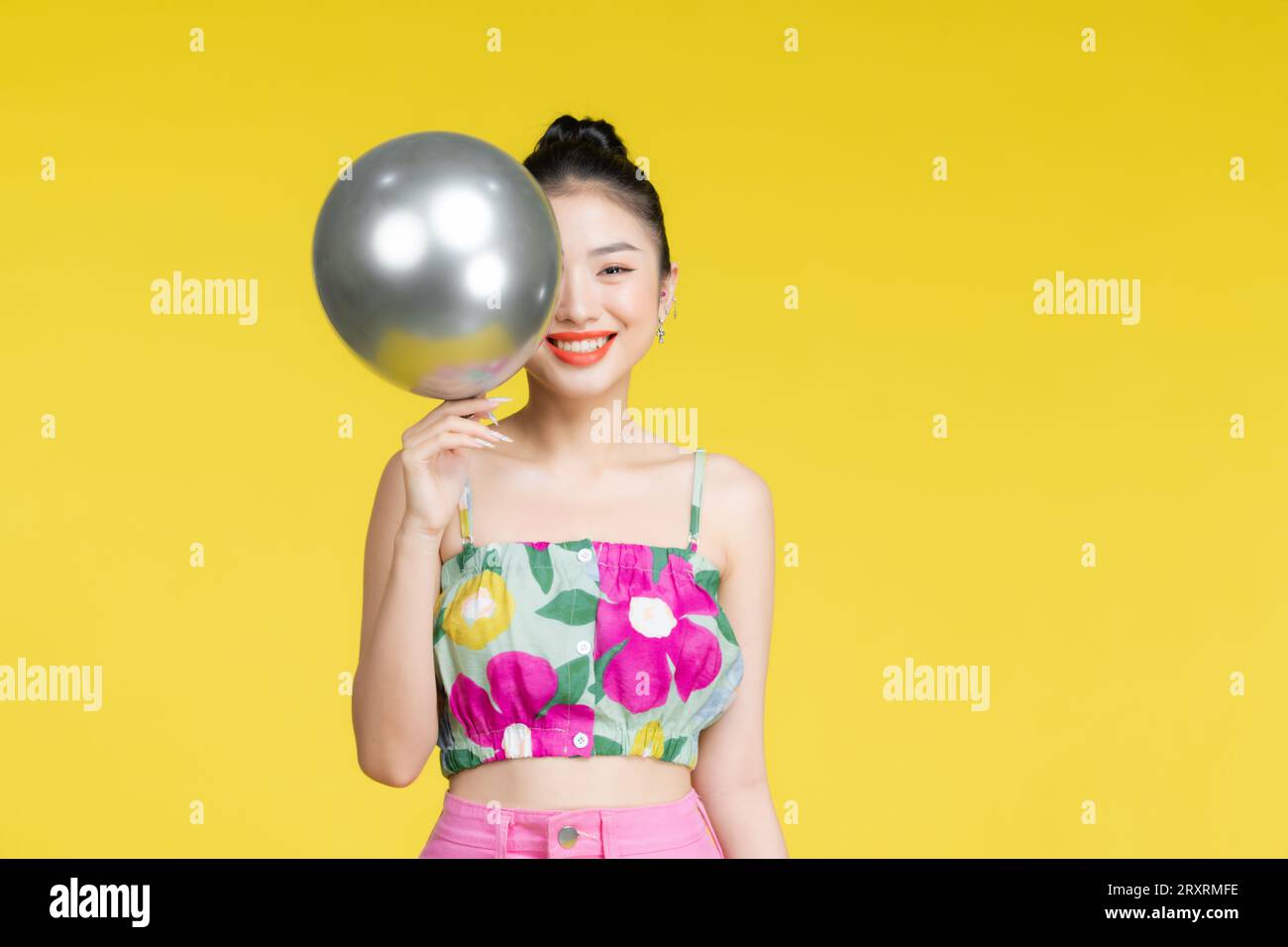 Giovane donna asiatica in abito alla moda con palloncino d'argento tra le mani Foto Stock