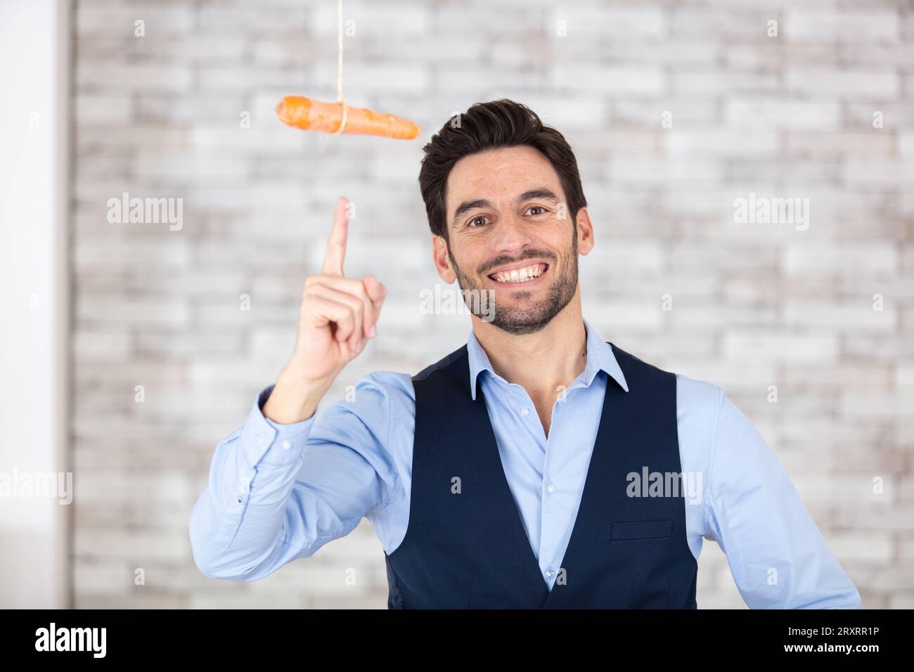 uomo d'affari che indica una carota penzolante Foto Stock