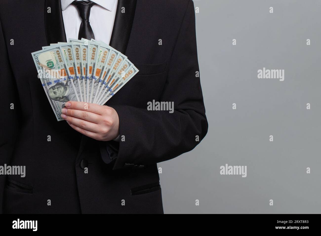 Uomo d'affari che detiene banconote in denaro in dollari americani su sfondo grigio Foto Stock