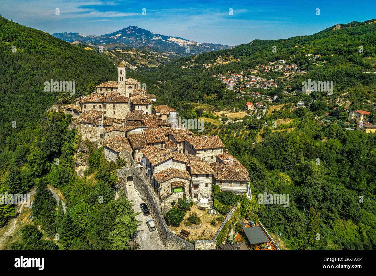 Veduta aerea di Castel Trosino circondata da verdi boschi con la chiesa di San Lorenzo Martire sulla sommità della scogliera in travertino. Regione Marche Foto Stock
