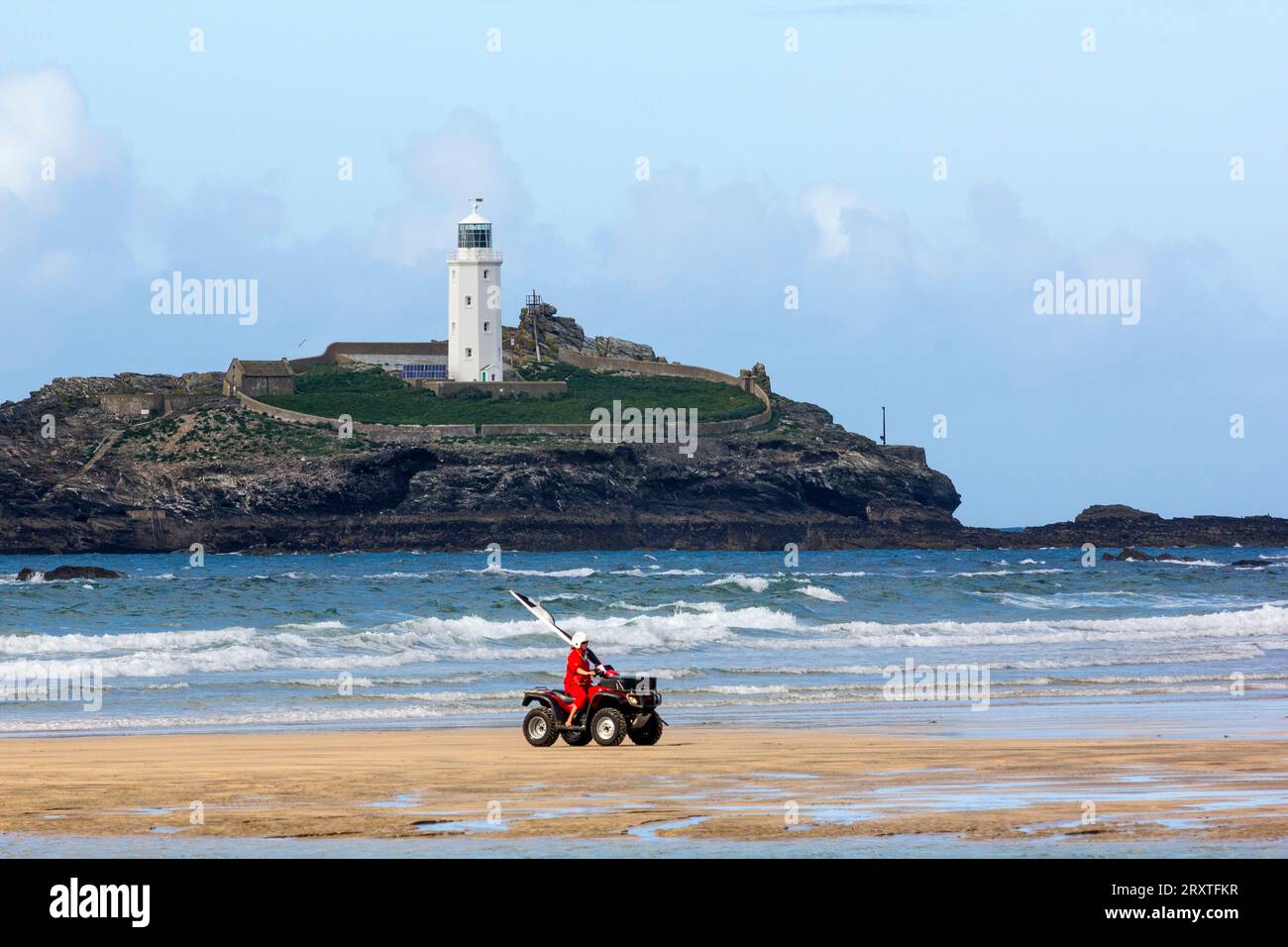 Guardia del corpo su un quad che sposta la bandiera di sicurezza a Low Tide, Godrevy Sands, Godrevy Island e Lighthouse con Atlantic Surf, Nr. Hayle, Cornovaglia, Regno Unito Foto Stock