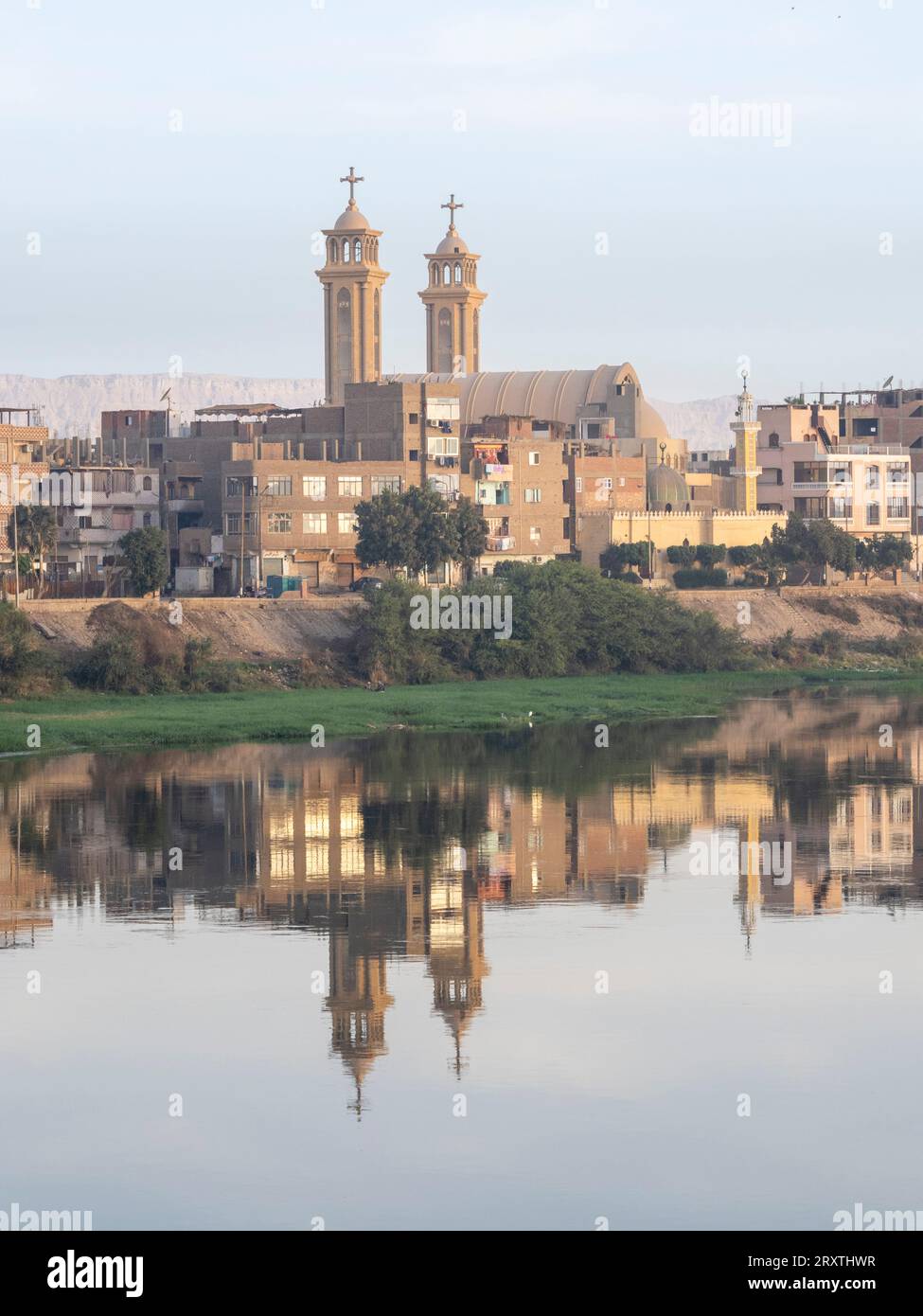 Una vista della costa lungo l'alto fiume Nilo, con la città e la chiesa riflettono, Dendera, Egitto, Nord Africa, Africa Foto Stock
