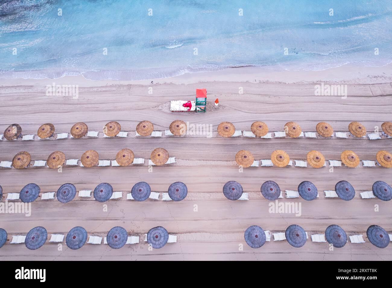 Vista aerea di file di ombrelloni da spiaggia con una torre di bagnino su una spiaggia sabbiosa, isola della Sicilia, Italia, Mar Mediterraneo, Europa Foto Stock