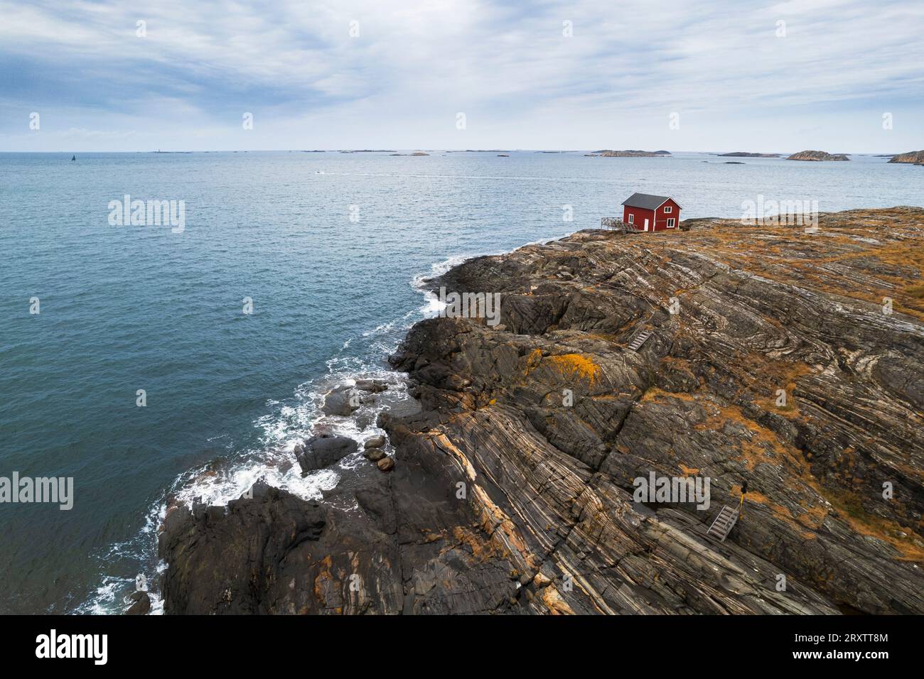 Casa solitaria rossa circondata dal mare sulla cima di una scogliera di un'isola rocciosa, Bohuslan, Vastra Gotaland, Svezia occidentale, Svezia, Scandinavia, Europa Foto Stock