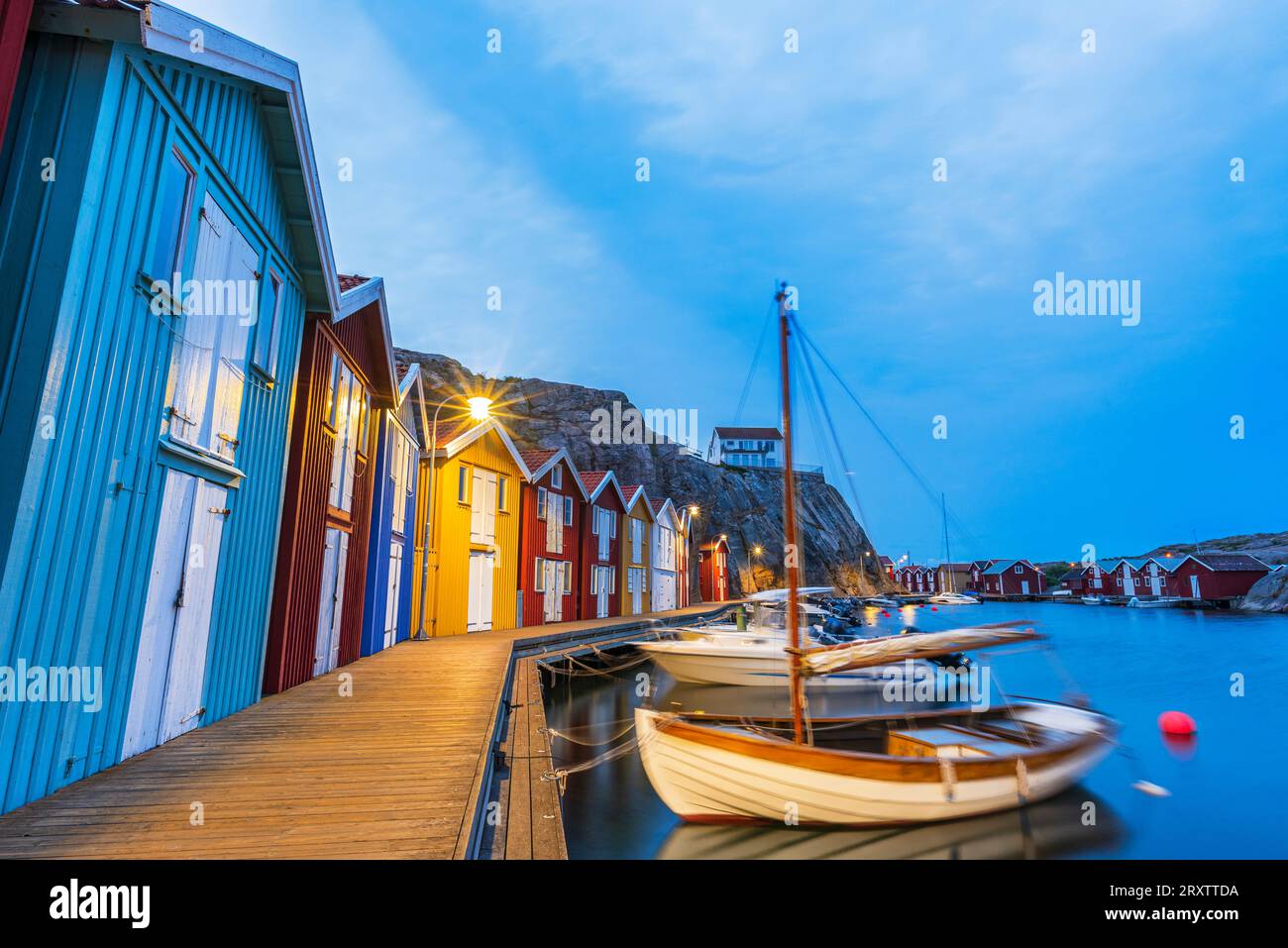 Capanne da pesca colorate con barca di legno ormeggiata al molo al tramonto, Smogen, Bohuslan, Vastra Gotaland, Svezia occidentale, Svezia, Scandinavia, Europa Foto Stock