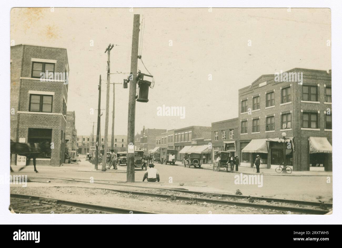 Una fotografia in bianco e nero del quartiere di Greenwood a Tulsa, OK. Nell'illustrazione sono raffigurate auto parcheggiate in strada, persone che camminano lungo i negozi e pali telefonici. Foto Stock