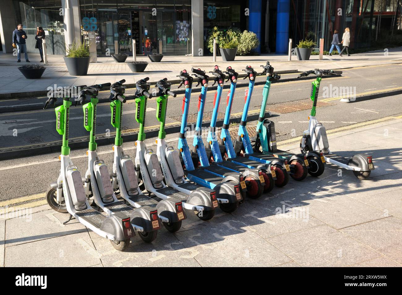 Una linea di scooter elettrici da Lime, Dott e Tier a noleggio/noleggio parcheggiati su un marciapiede di Londra. scooter elettrico, e scooter, e scooter, uk Foto Stock