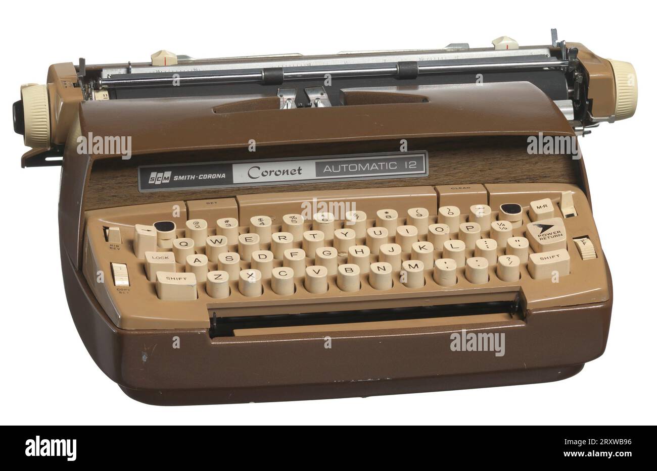 Una macchina da scrivere marrone scuro e chiaro con tasti bianchi. Nella parte anteriore della macchina da scrivere è presente un pannello di legno con un'etichetta che riporta ¿SCM / SMITH-CORONA / Coronet / AUTOMATIC 12.¿ la macchina da scrivere è elettrica e ha un cavo e una spina bianchi. In bianco sul retro della macchina da scrivere è ¿SCM / SMITH-CORONA / MADE IN U.S.A.¿ un nastro d'inchiostro ancora attaccato alla macchina da scrivere. Foto Stock