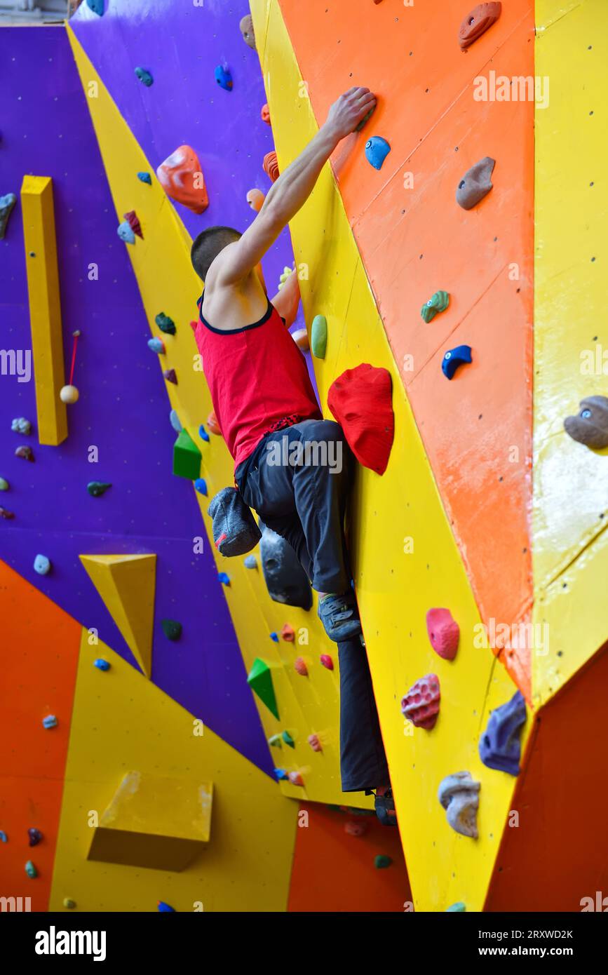Arrampicata libera uomo su Color Practice Wall interni Foto Stock