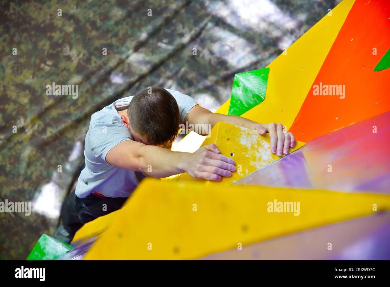 Arrampicata libera uomo su Color Practice Wall interni Foto Stock