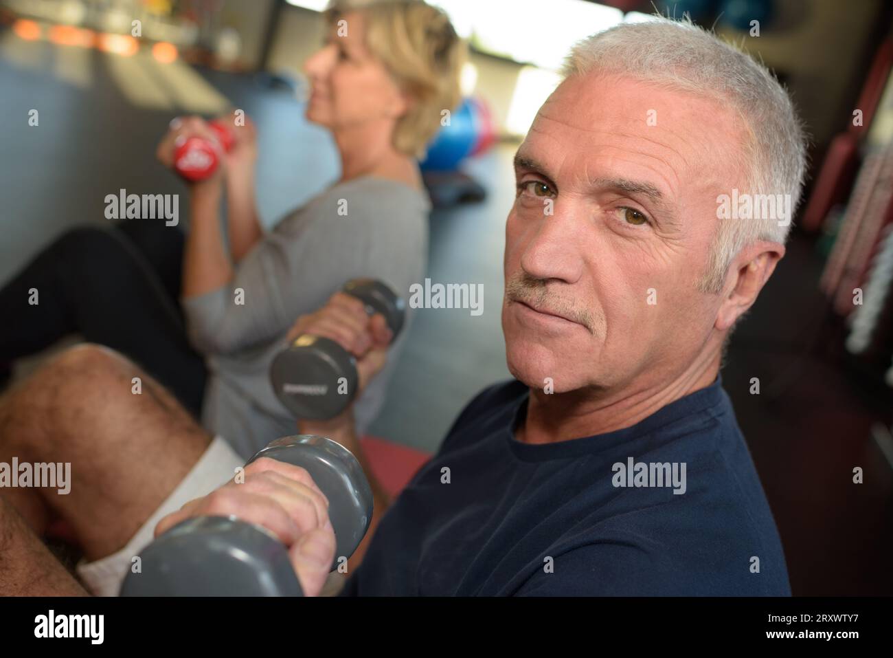 vecchio uomo positivo che guarda la macchina fotografica in palestra Foto Stock