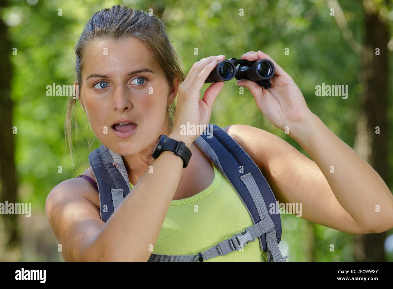 giovane donna che usa un binocolo che sembra molto sorpresa Foto Stock