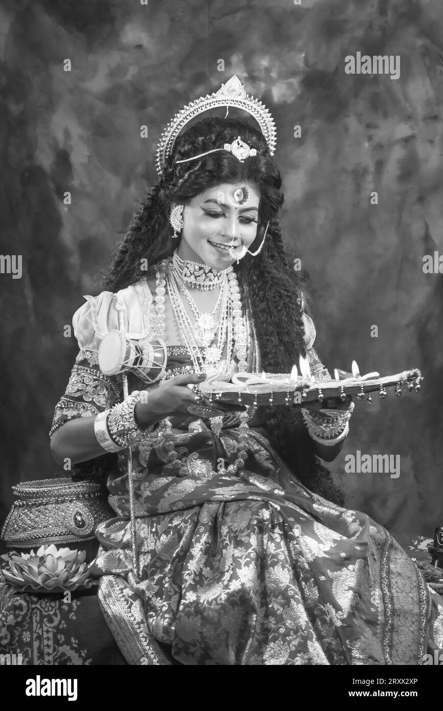 Ritratto della bellissima ragazza indiana di Durga Idol Agomoni Concept foto al coperto che indossa il tradizionale sari indiano, gioielli in oro e braccialetti. Maa Durga Foto Stock