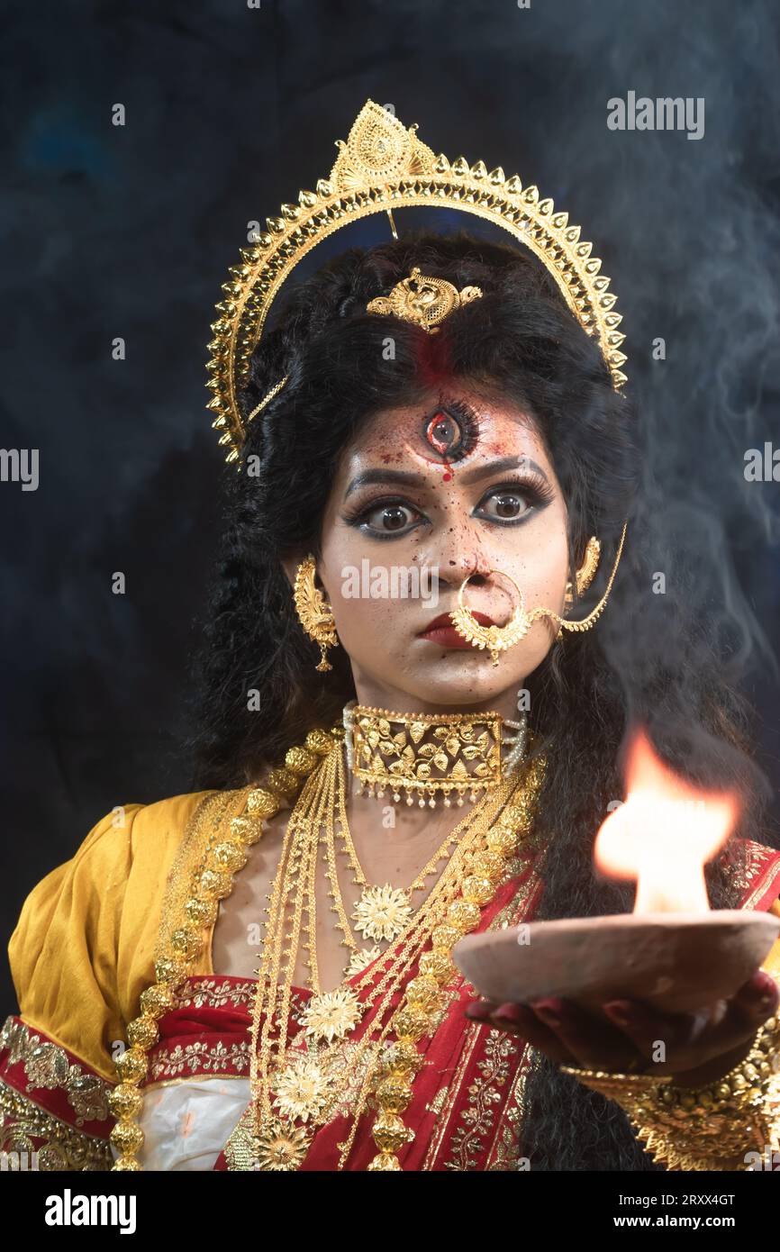 Ritratto della bellissima ragazza indiana di Durga Idol Agomoni Concept foto al coperto che indossa il tradizionale sari indiano, gioielli in oro e braccialetti. Maa Durga Foto Stock