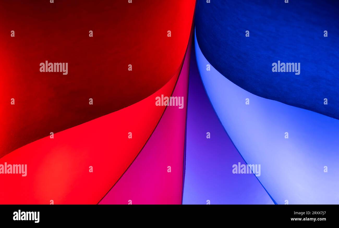 Primo piano delle forme curve di colore rosso e blu realizzate per normali fogli di carta bianca e luci colorate Foto Stock