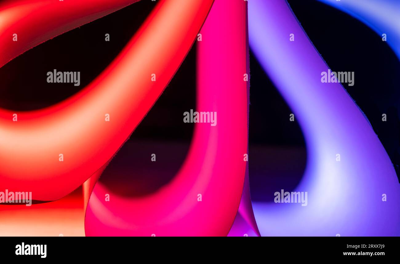 Primo piano delle forme curve di colore rosso e blu realizzate per normali fogli di carta bianca e luci colorate Foto Stock
