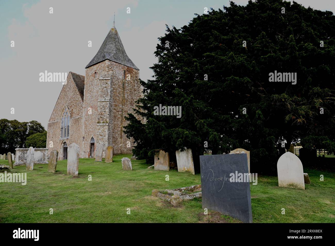 La semplice lapide di ardesia grigia di Derek Jarman nel cimitero della chiesa di St Clement, New Romney, Romney Marsh Kent. La lapide porta solo il suo nome. Foto Stock