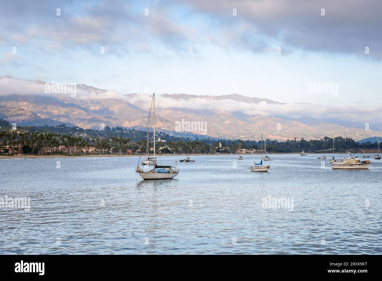 Gli yacht sono ancorati al largo della spiaggia di Santa Barbara al tramonto in autunno. Montagne torreggianti sono sullo sfondo. Foto Stock