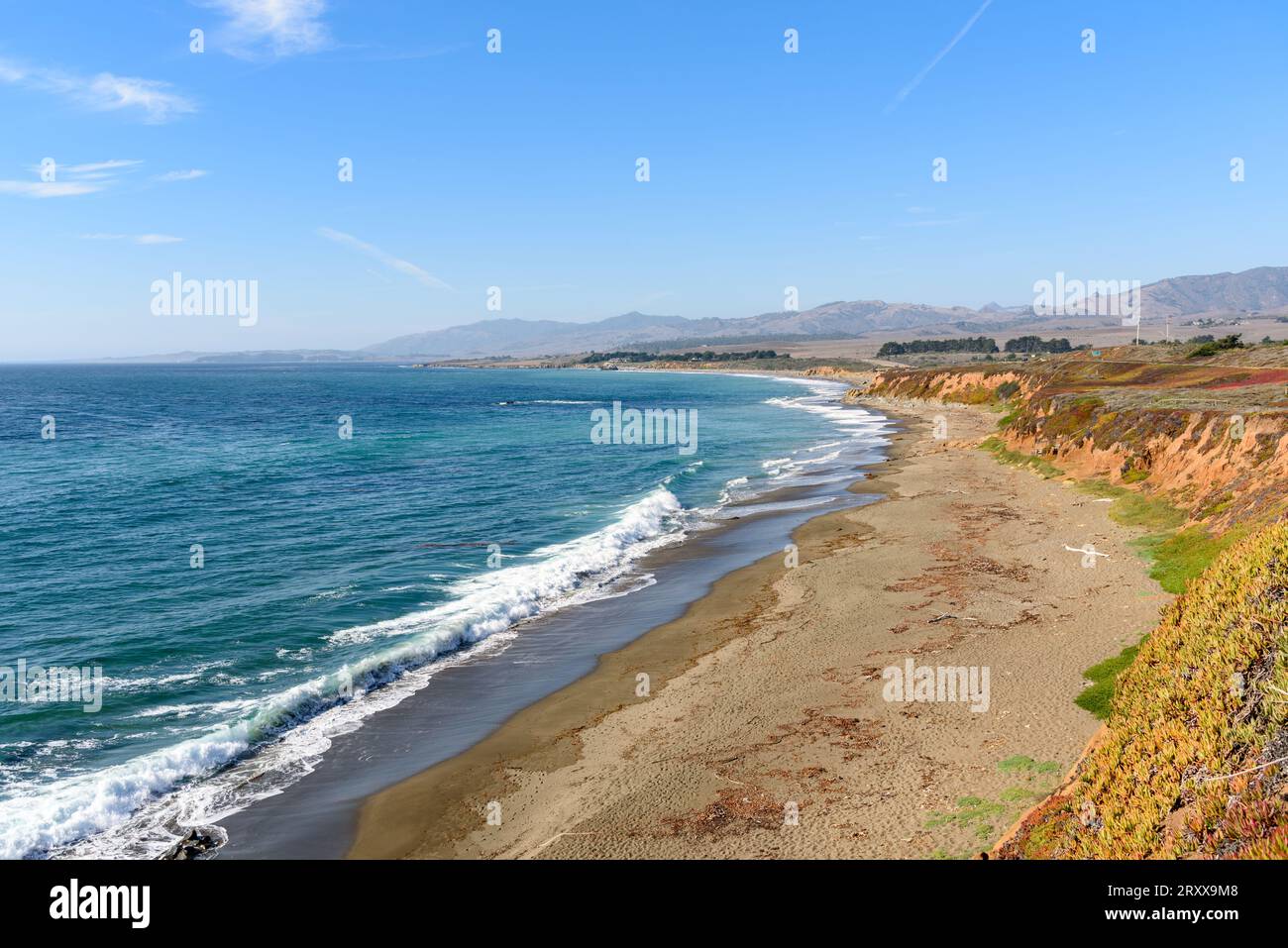 Spiaggia deserta ai piedi di una scogliera lungo la costa della California in una chiara giornata autunnale. La prima strada statale della Califronia è visibile in lontananza. Foto Stock