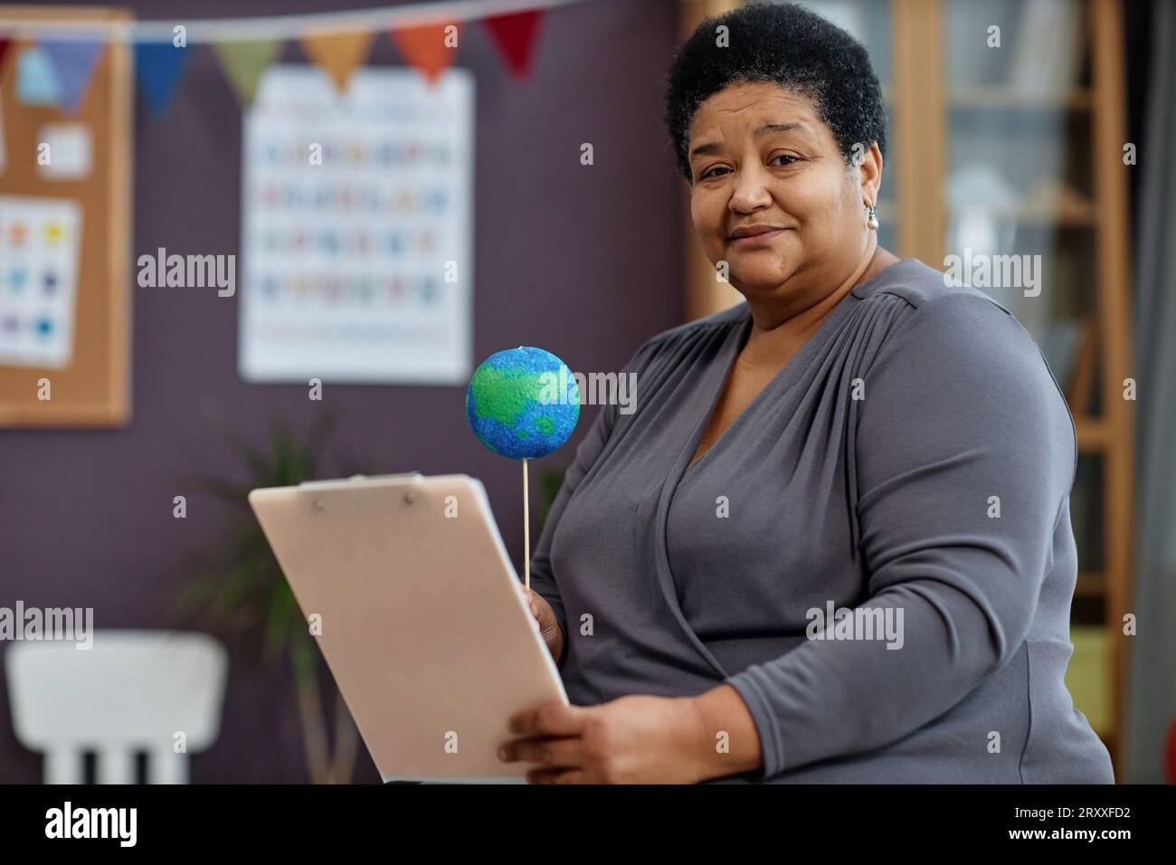 Ritratto di una donna di colore come insegnante donna che tiene gli appunti in età prescolare e guarda la fotocamera e lo spazio di copia Foto Stock