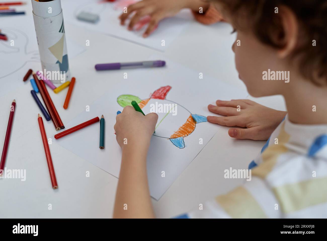 Primo piano di un ragazzo che colora le tartarughe marine al tavolo durante la lezione di arte e artigianato nella scuola materna, spazio per le copie Foto Stock
