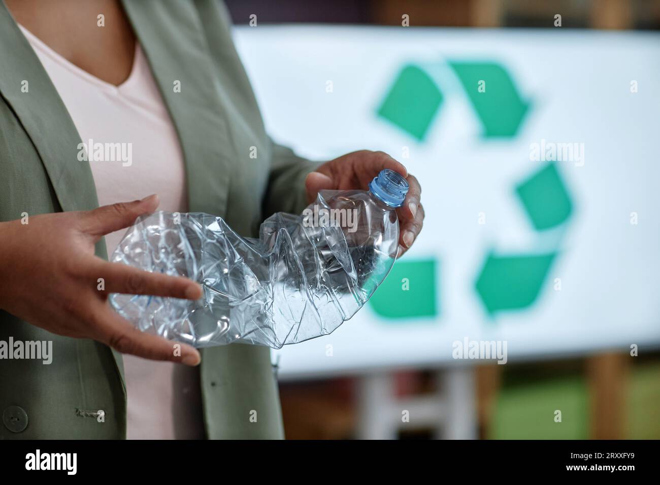 Primo piano di una professoressa che tiene una bottiglia di plastica nella classe di smistamento e riciclaggio dei rifiuti, nello spazio per le copie Foto Stock