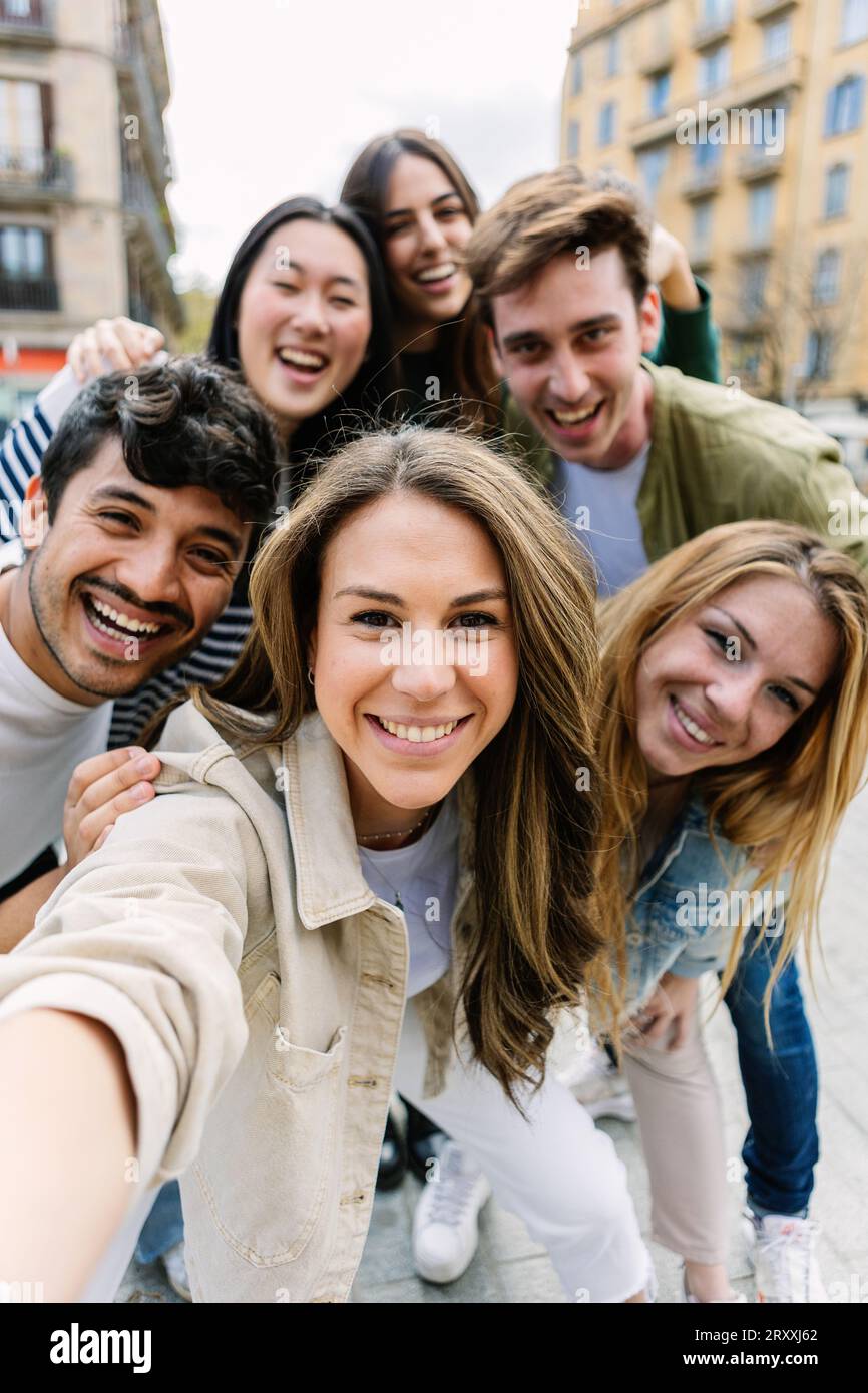 Scatto verticale di giovani millennial che scattano selfie con il telefono in città Foto Stock