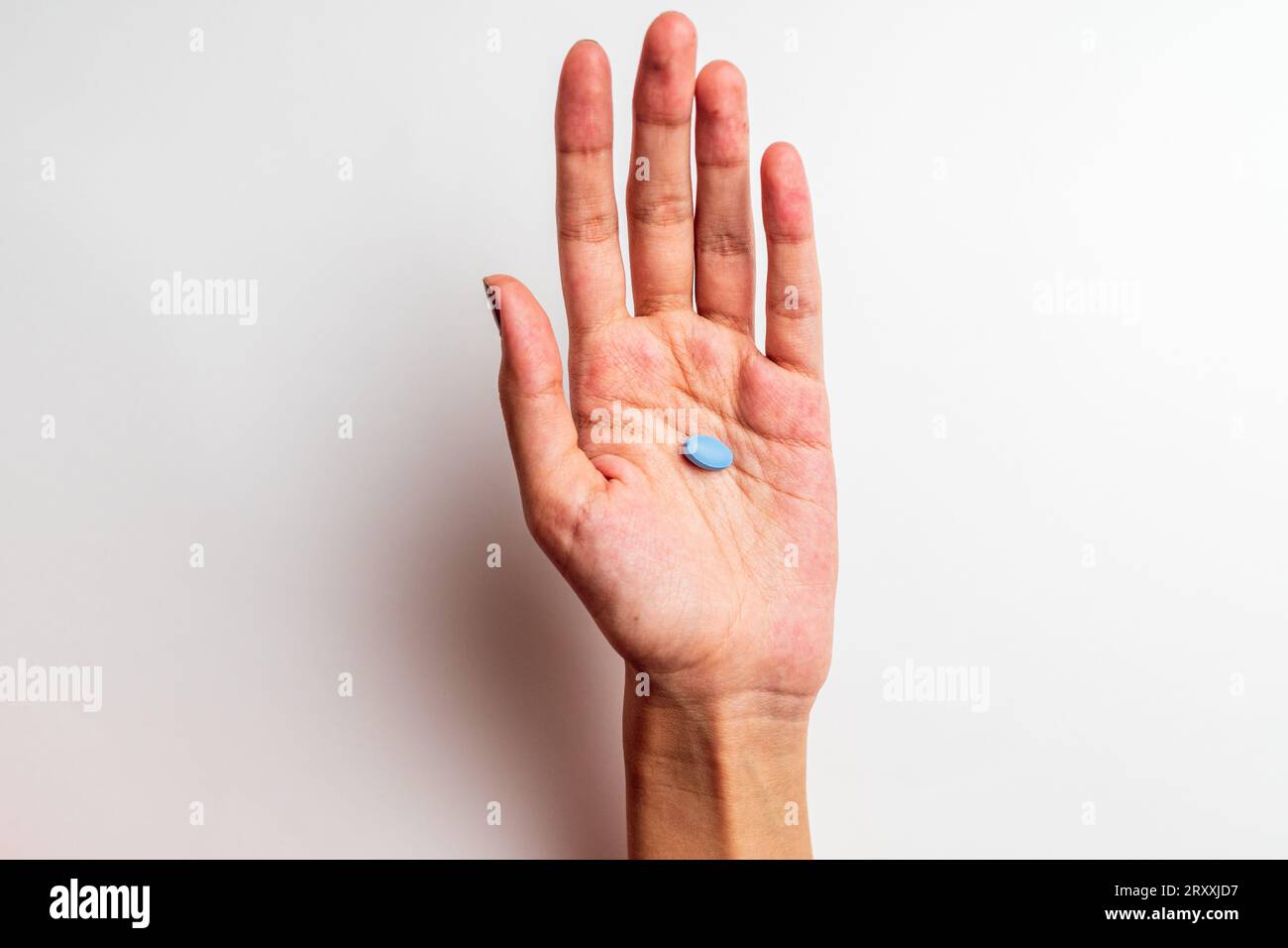 La mano di una donna che tiene una pillola, isolata sullo sfondo bianco Foto Stock