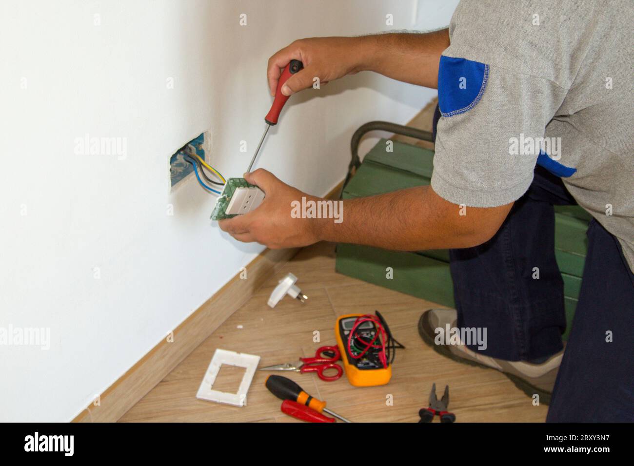 Immagine di un elettricista addetto alla riparazione e all'installazione di una presa elettrica domestica. Presa di alimentazione fai da te. Foto Stock