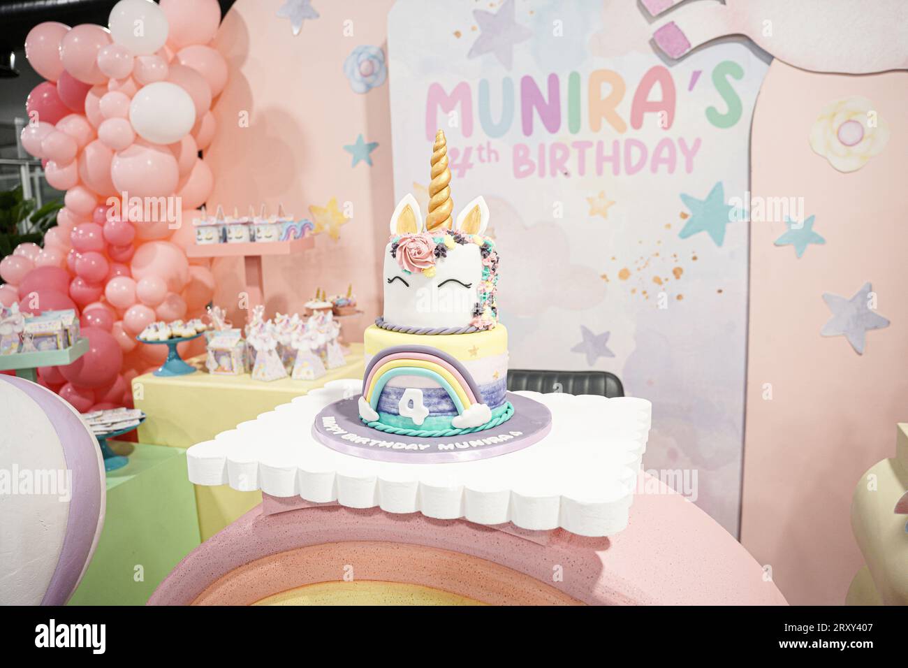 Torta di compleanno unicorno decorata con arcobaleno e corno d'oro, palloncini e spuntini. Torta Unicorn Birthday Party, quarto compleanno di Sara Foto Stock
