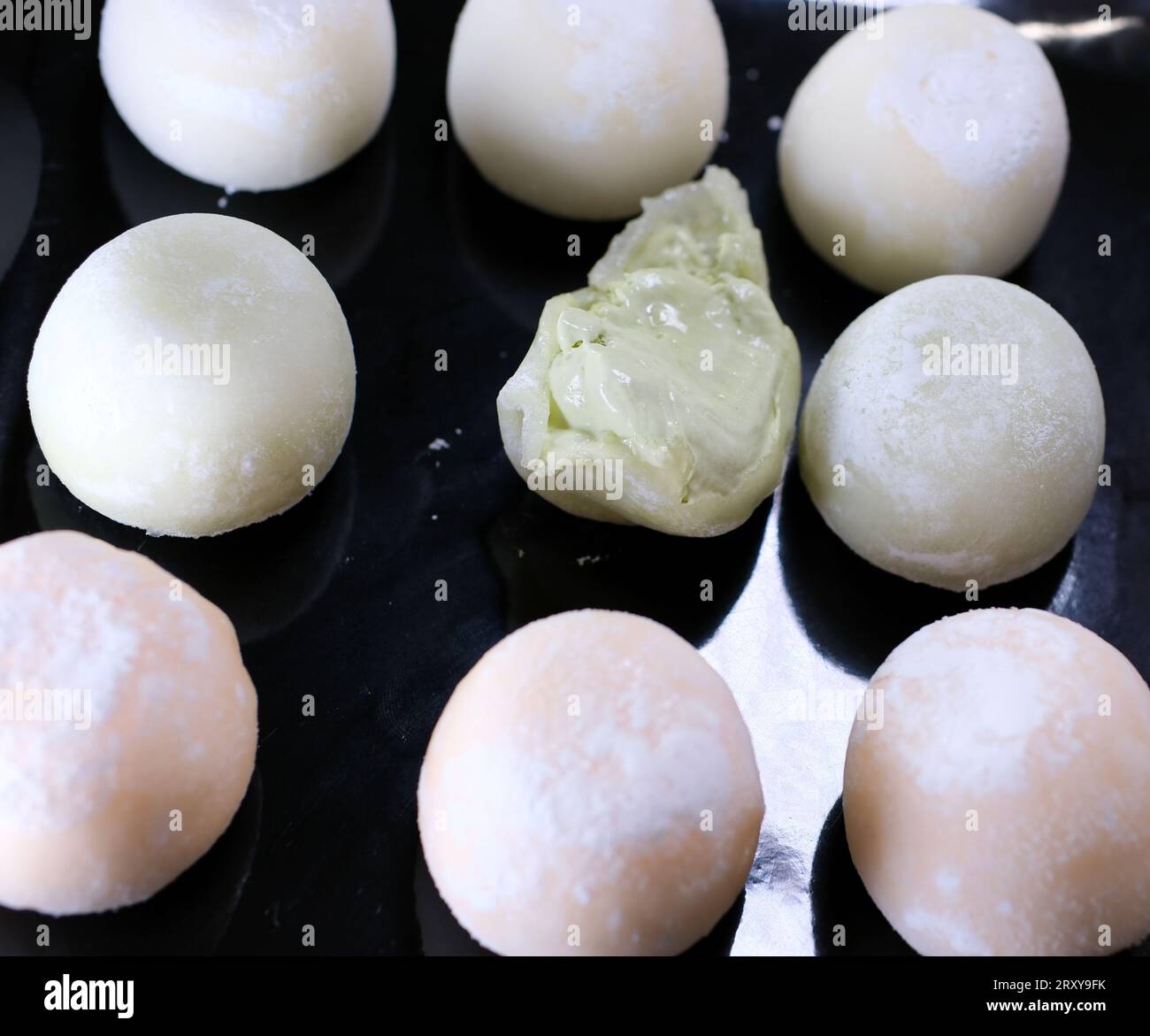 Gelato mochi su piatto nero con gusto di tè verde, popolare farina di riso asiatica. prendete un boccone di dessert e rimettetelo Foto Stock