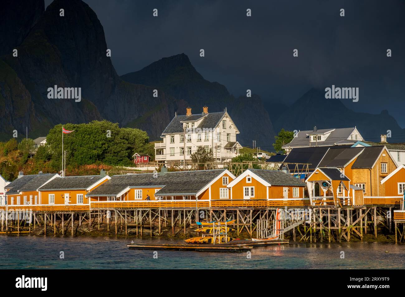 L'immagine cattura la bellezza delle tradizionali abitazioni a palafitte che circondano un fiordo nel Lofoten. La scena è arricchita da un suggestivo paesaggio nuvoloso e dalla S Foto Stock
