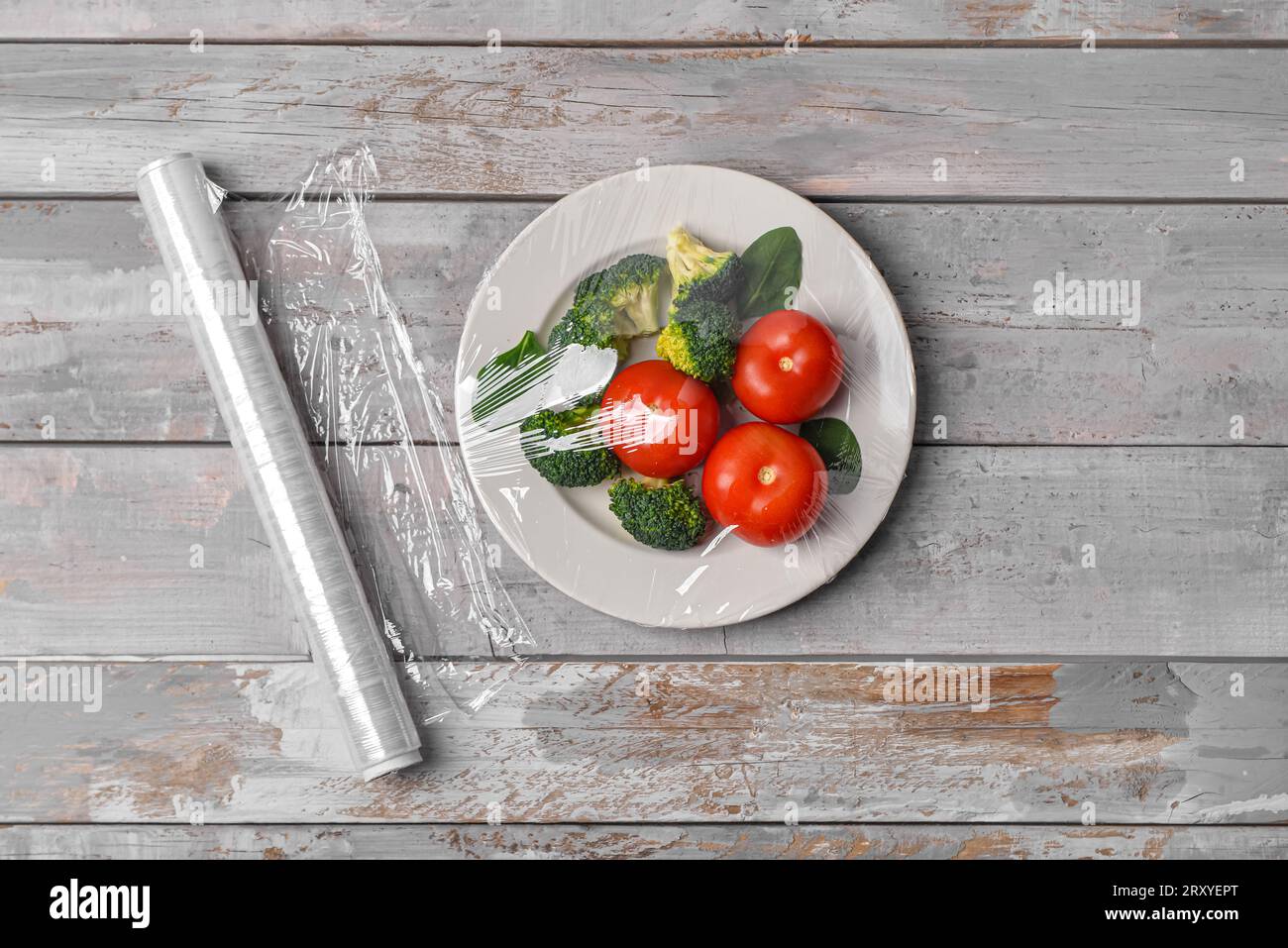 Piatto con verdure avvolto con fascia elastica su fondo grigio in legno Foto Stock