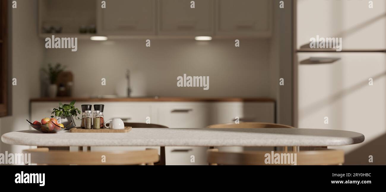 Un tavolo da pranzo con bottiglie di condimento, una pianta in vaso, accessori e spazio copia su una moderna cucina bianca sfocata sullo sfondo. primo piano ima Foto Stock
