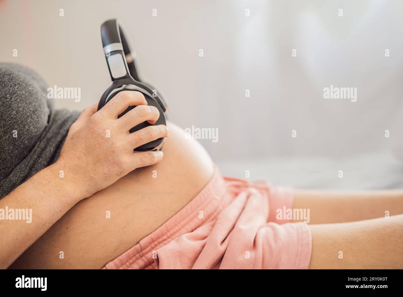 Melodie nell'utero: Cuffie posizionate su una pancia incinta, che si legano attraverso la musica, una commovente connessione tra madre e bambino Foto Stock