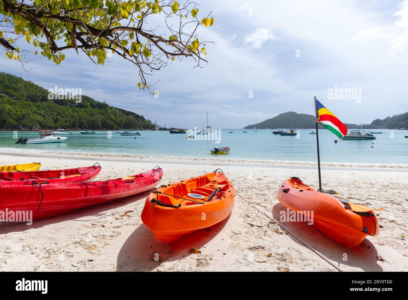 Paesaggio di spiaggia con kayak di plastica rossi e bandiera delle Seychelles in una giornata di sole Foto Stock