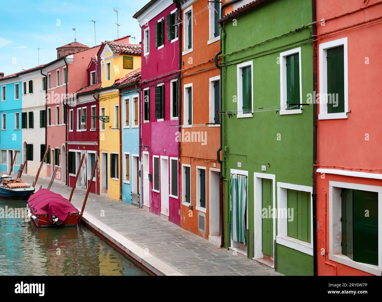 Esterno di case multicolore situate vicino al canale con tradizionali gondole nell'Isola di Burano, Venezia, Italia Foto Stock