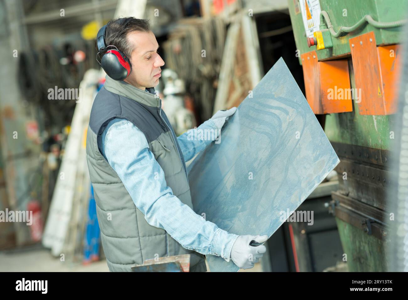 uomo che tiene una lamiera in fabbrica Foto Stock