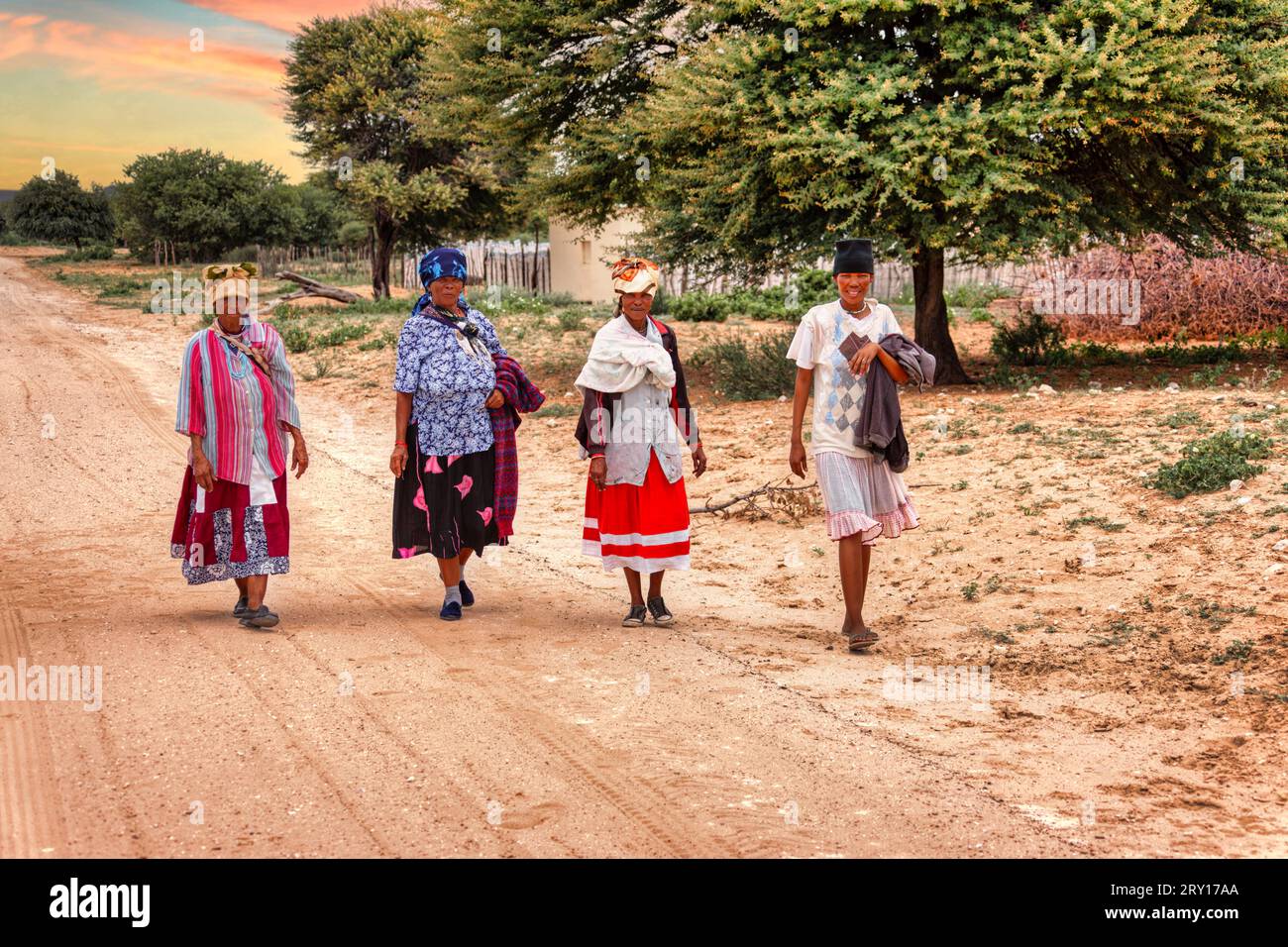 quattro donne africane basarwa camminano su una strada sterrata nel villaggio tradizionale Foto Stock